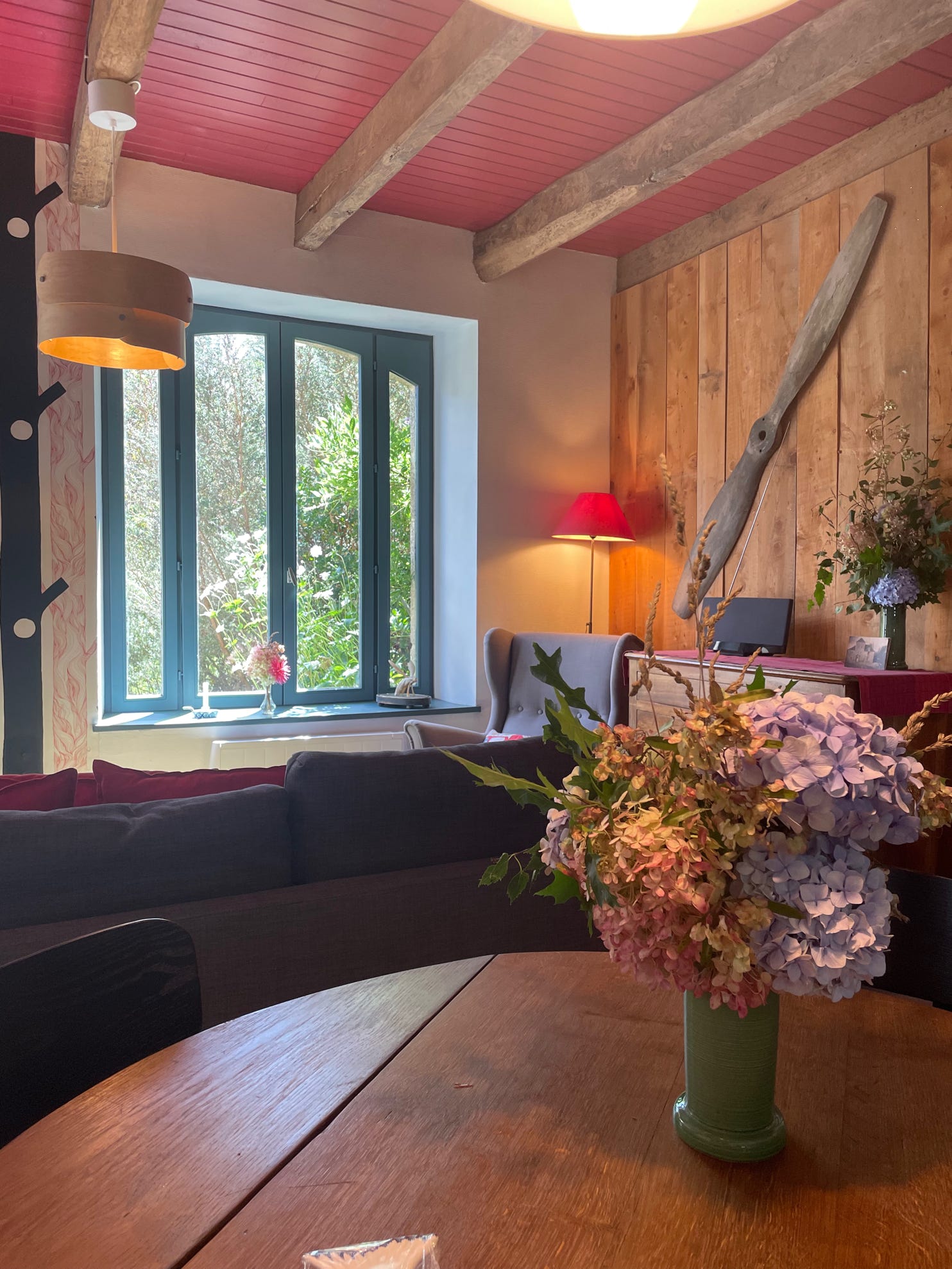 Vue de la table à manger vers le salon et la grande fenêtre quo donne sur la terrasse et le jardin avec vue sur le Manoir de Goaz Froment