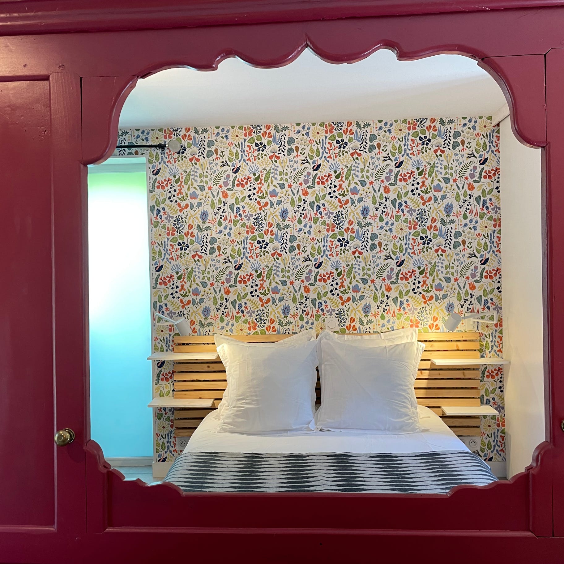 Un panneau de lit clos breton en rouge Farrow & Ball sépare le studio La Maison du Four entre espace jour et nuit