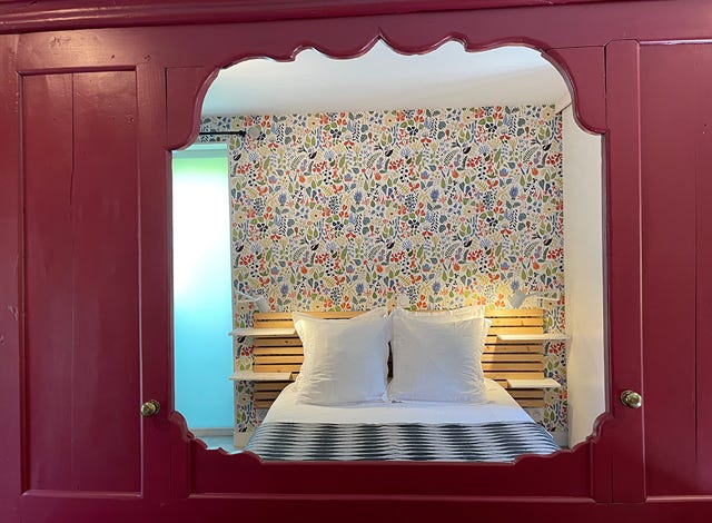 Un panneau de lit clos breton en rouge Farrow & Ball sépare le studio La Maison du Four entre espace jour et nuit 