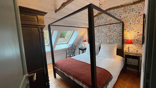 Lit à baldaquin dans la chambre double dans le gîte La Grange du manoir avec papier peint suédois et vue sur le manoir et son parc au calme